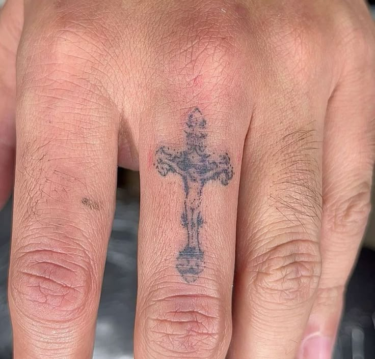 a hand with a cross tattoo on it