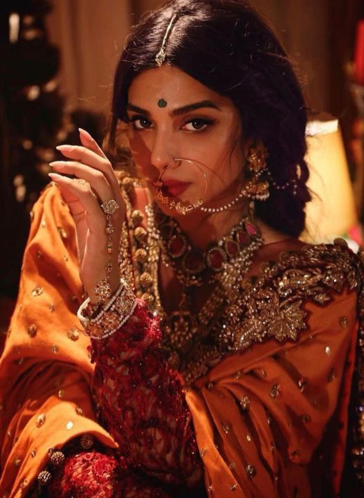 a woman in an orange outfit with jewelry on her face