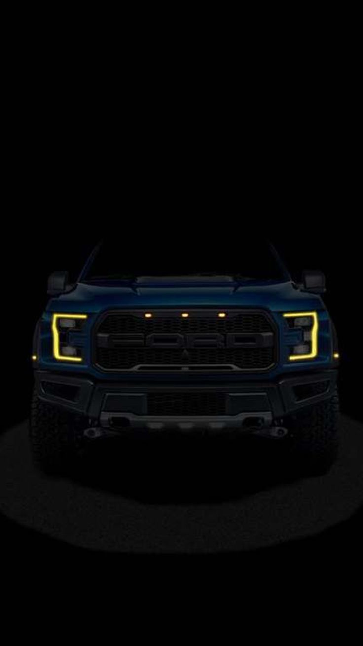 the front end of a blue pickup truck with its lights turned on in the dark