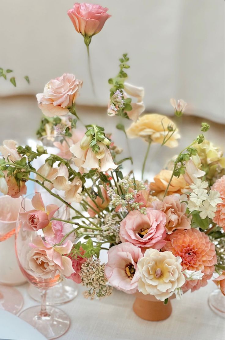 a vase filled with lots of flowers sitting on top of a white tablecloth covered table