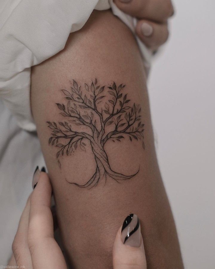 a woman's arm with a tree tattoo on the left side of her body