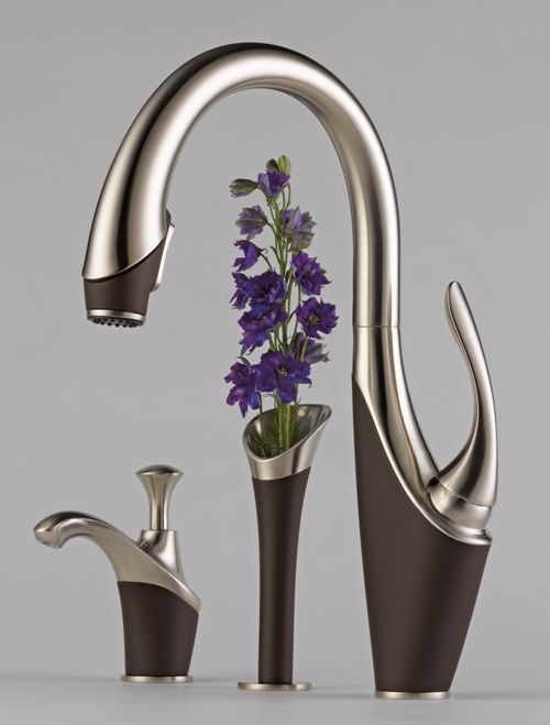 a sink with two faucets and purple flowers in it