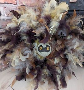 a wreath made out of feathers with an owl face