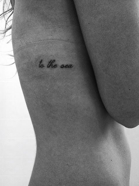 a woman's chest with the words to the sea tattooed on it