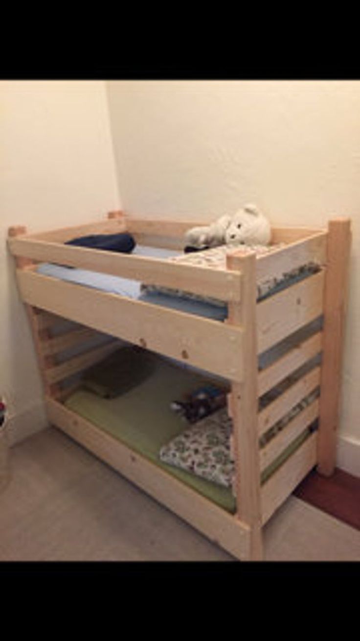 a wooden bunk bed sitting next to a wall with a stuffed animal on top of it