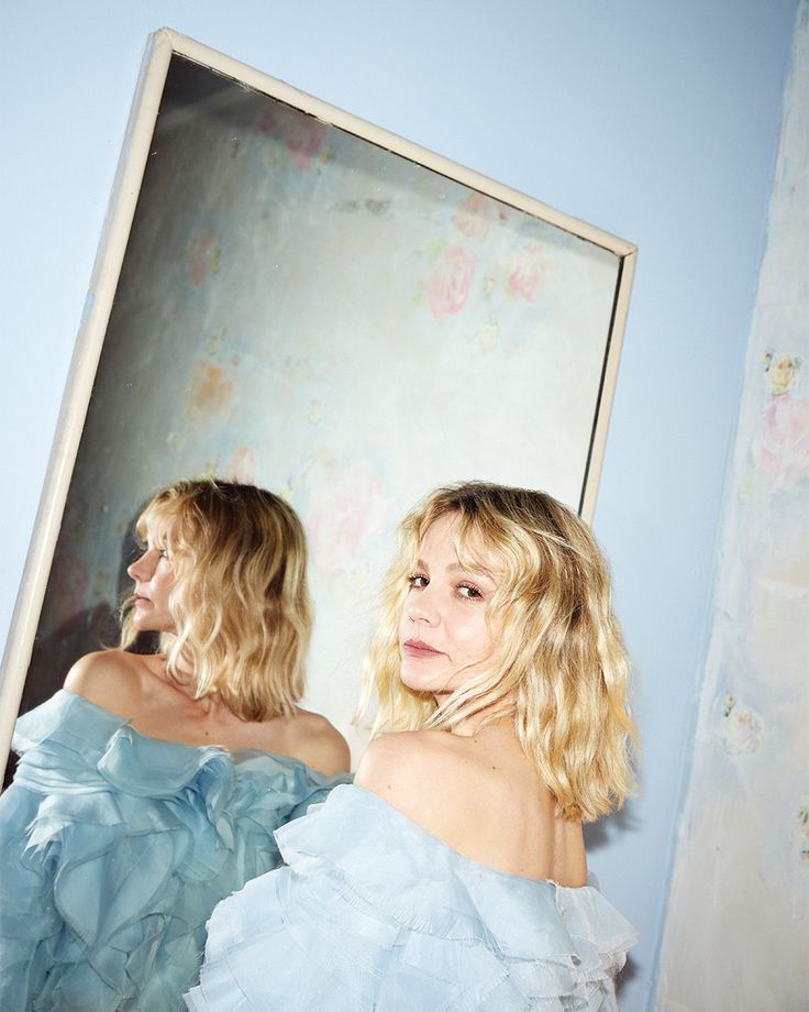 two women standing in front of a mirror with one woman's reflection on the wall