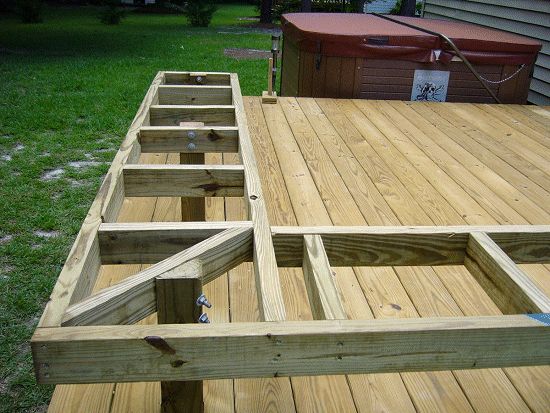 a wooden deck is being built in front of a house with hot tubs on it