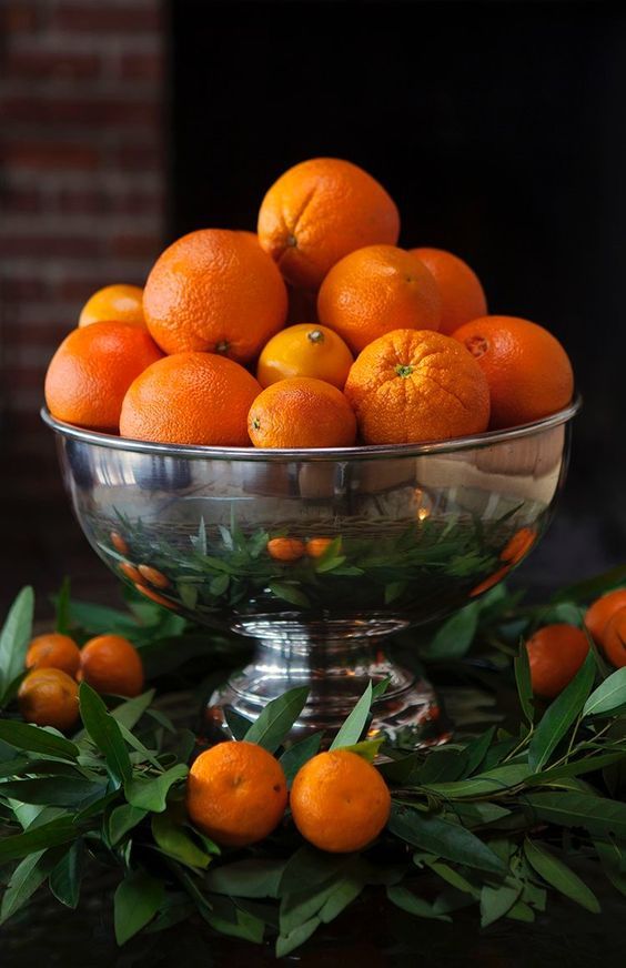 a bowl filled with lots of oranges on top of a table