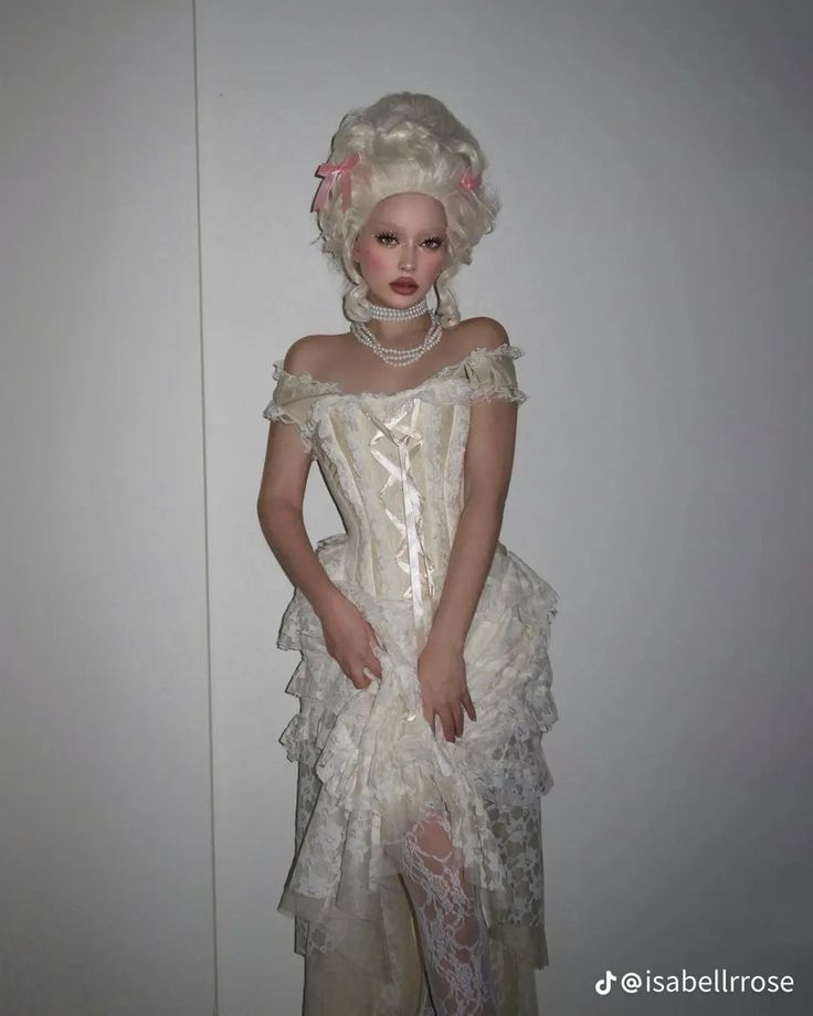 a doll dressed in white is standing next to a wall