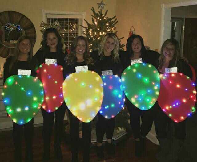 a group of women standing next to each other in front of a christmas tree holding balloons