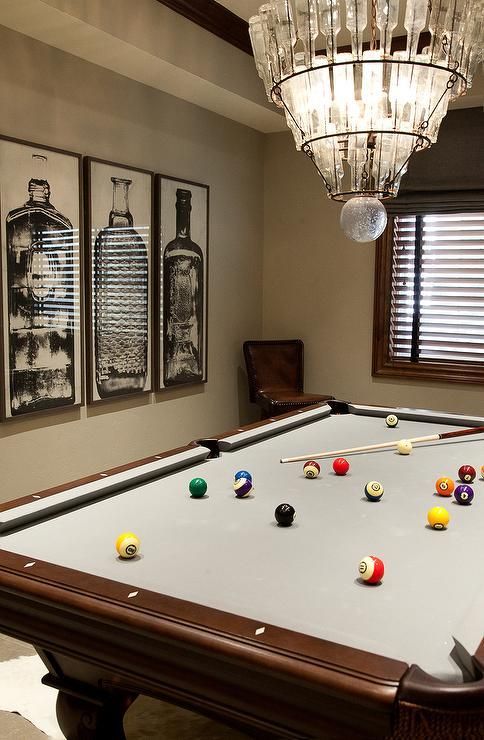 a pool table in a room with pictures on the wall and chandelier above it