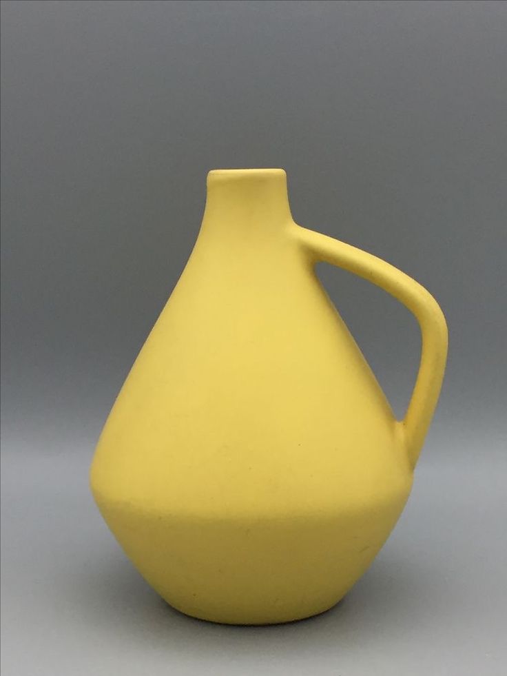 a yellow vase sitting on top of a table