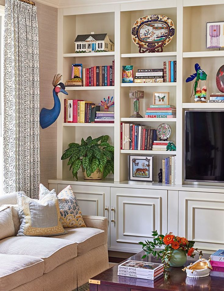 a living room filled with lots of furniture and bookshelves covered in shelves next to a window