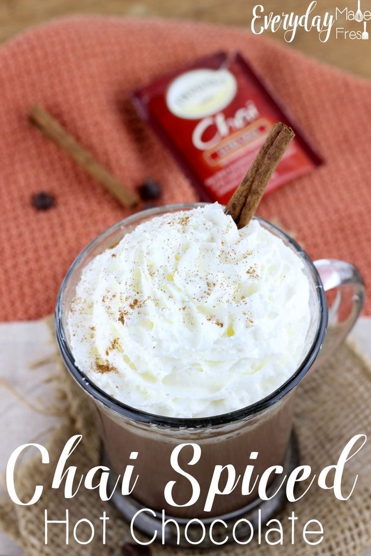 chai spiced hot chocolate in a glass mug with cinnamon sticks on the side