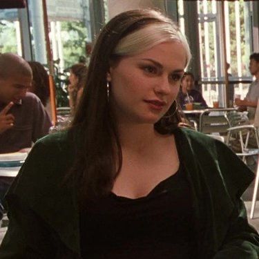 a woman is sitting at a table with food in front of her and looking off to the side