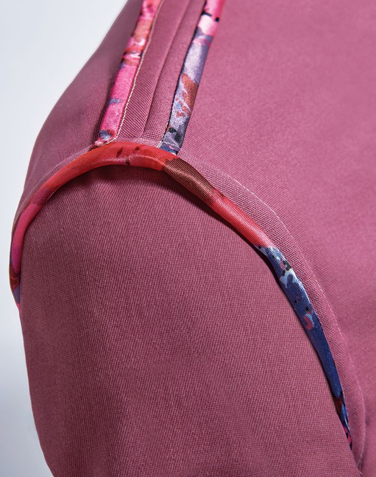 a close up view of the zippers on a pink bag with floral print and red lining