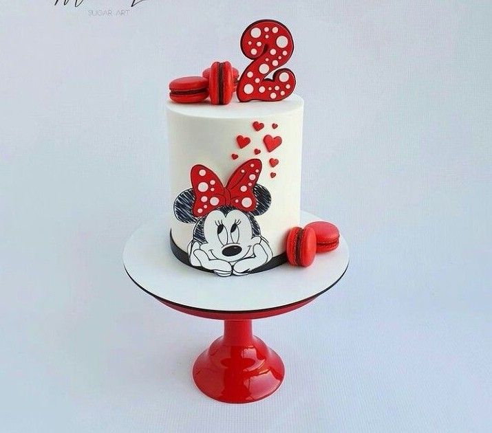 a cake with minnie mouse decorations on it is sitting on a red stand and white background