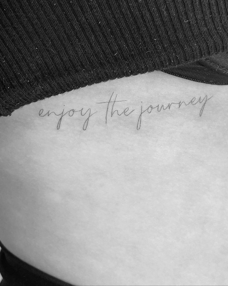 a woman's lower back with the words enjoy the journey written on her stomach