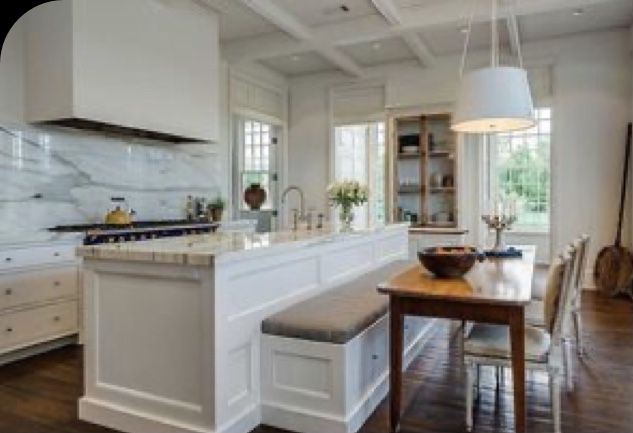 a large kitchen with white cabinets and wood flooring, along with a dining room table