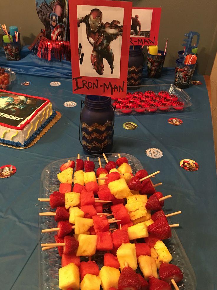 a table topped with lots of fruit and veggies next to a sign that says iron man