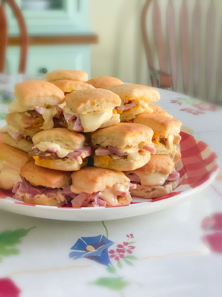 a pile of sandwiches sitting on top of a white plate next to a pink flowered table cloth