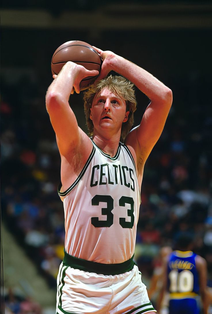 a man holding a basketball while standing on top of a court with his hands in the air