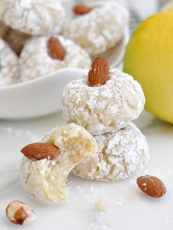 almonds and powdered sugar are piled on top of each other in front of a lemon