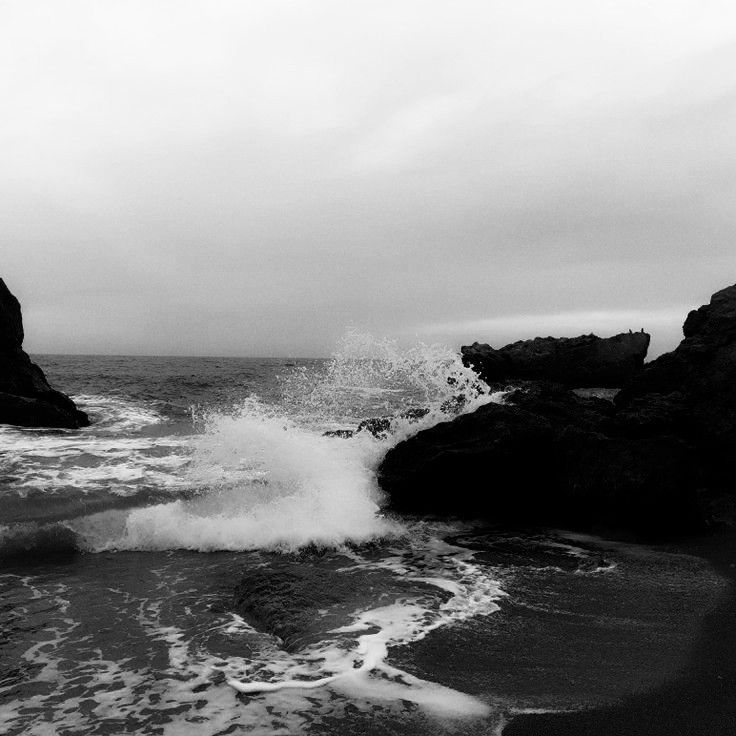 black and white photograph of waves crashing on rocks