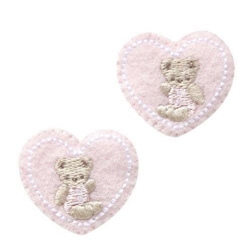 two pink heart shaped patches with a teddy bear on one side and a white background