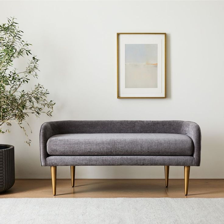 a grey couch sitting next to a potted plant