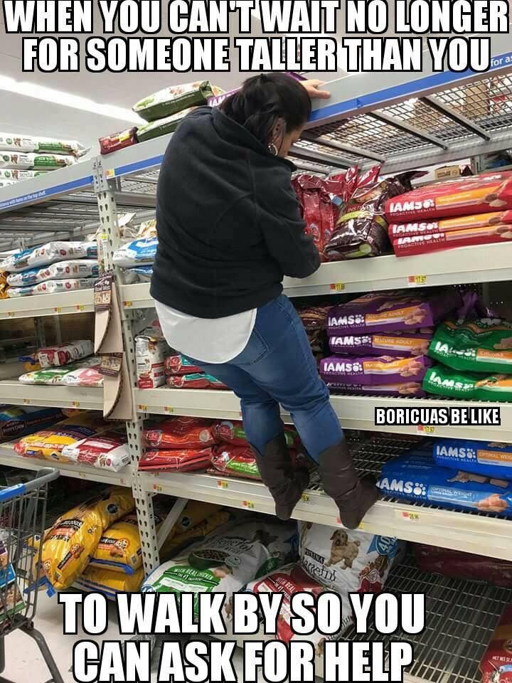 a woman is trying to pick up food in the store aisle while she's on her cell phone