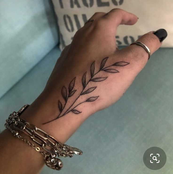 a woman's hand with a tattoo on it and a bracelet around her wrist