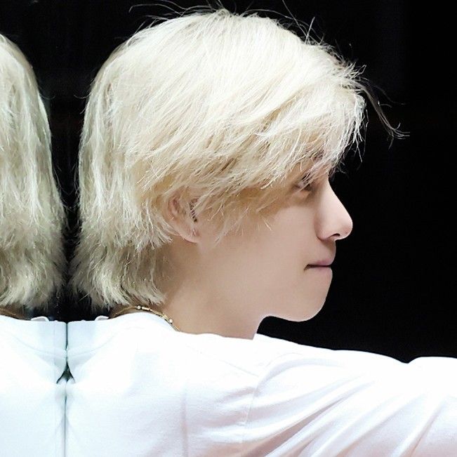 a person with blonde hair is taking a selfie in front of a mirror and wearing a white t - shirt