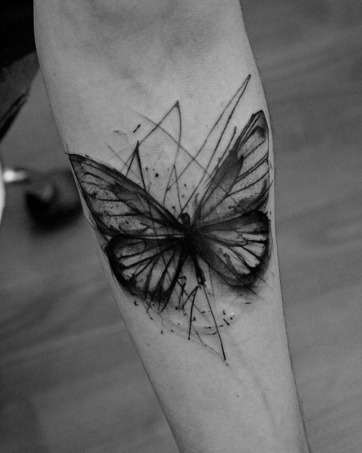 a black and white photo of a butterfly tattoo on the left leg with lines coming out of it