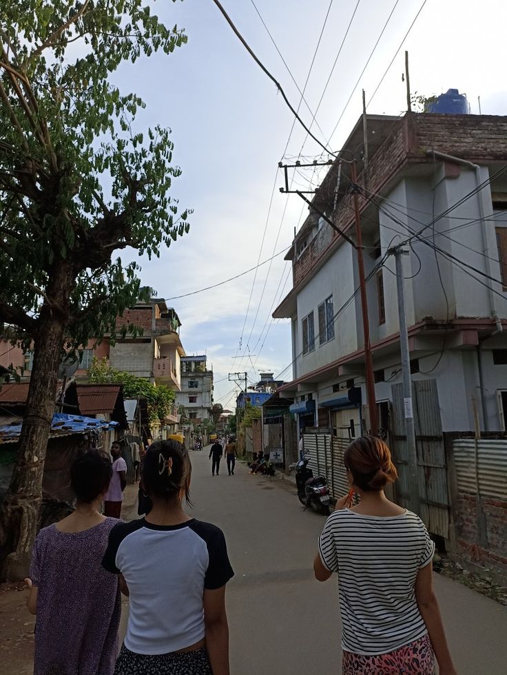 two women walking down the street in front of some buildings and people on bikes behind them