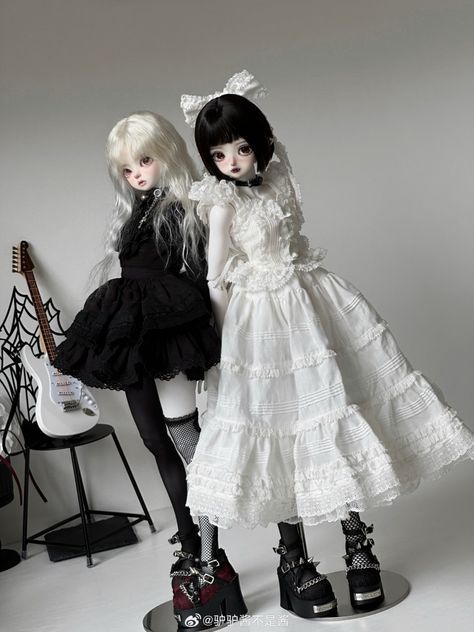 two dolls standing next to each other in black and white outfits