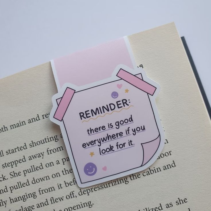 an open book with a pink sticker on the front and back of it that reads reminder there is good everywhere if you look for it