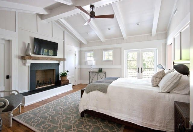 a bedroom with a bed, fireplace and ceiling fan in the middle of the room