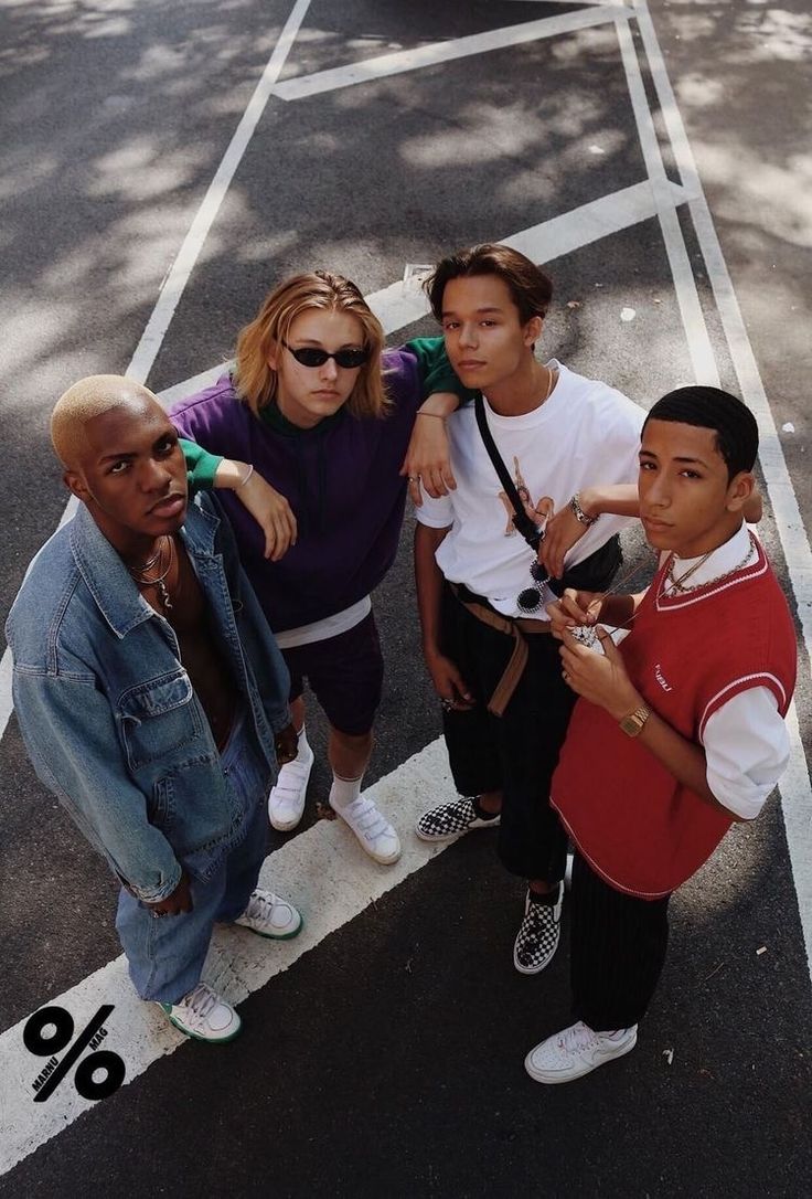 four people standing in the middle of a parking lot with one person taking a selfie