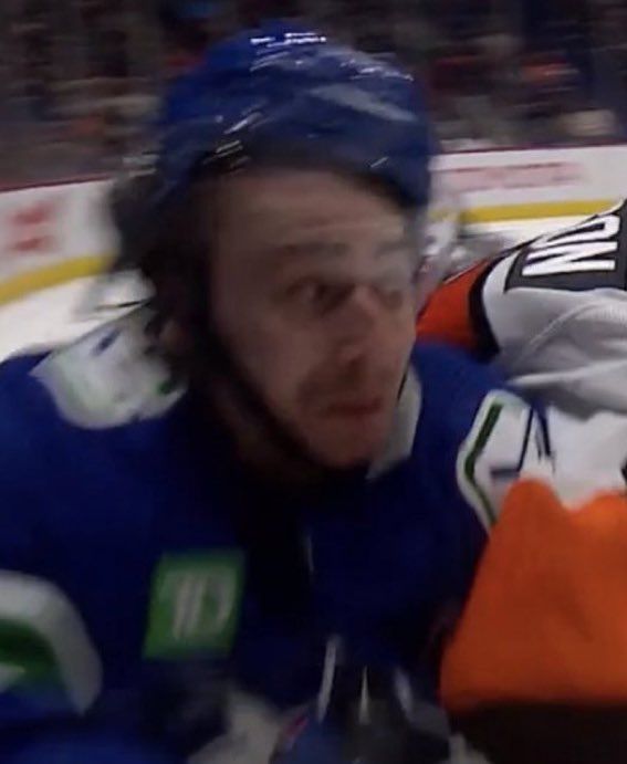 a hockey player is looking at the camera while he's being filmed by another player