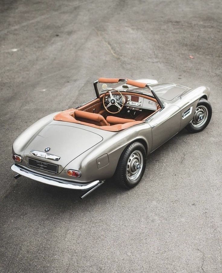 an old model car is parked on the street in front of some concrete pavements