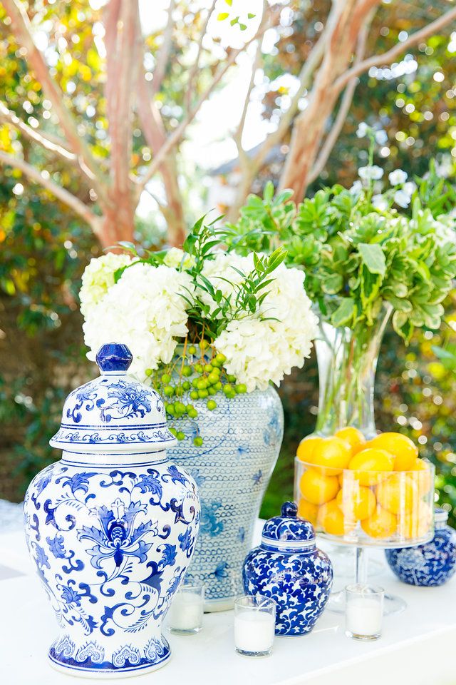 blue and white vases with lemons, hydrangeas and flowers on a table