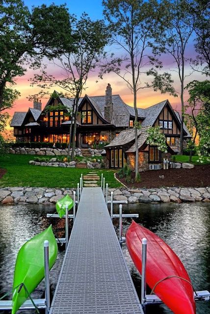 two canoes are docked at the end of a dock in front of a house