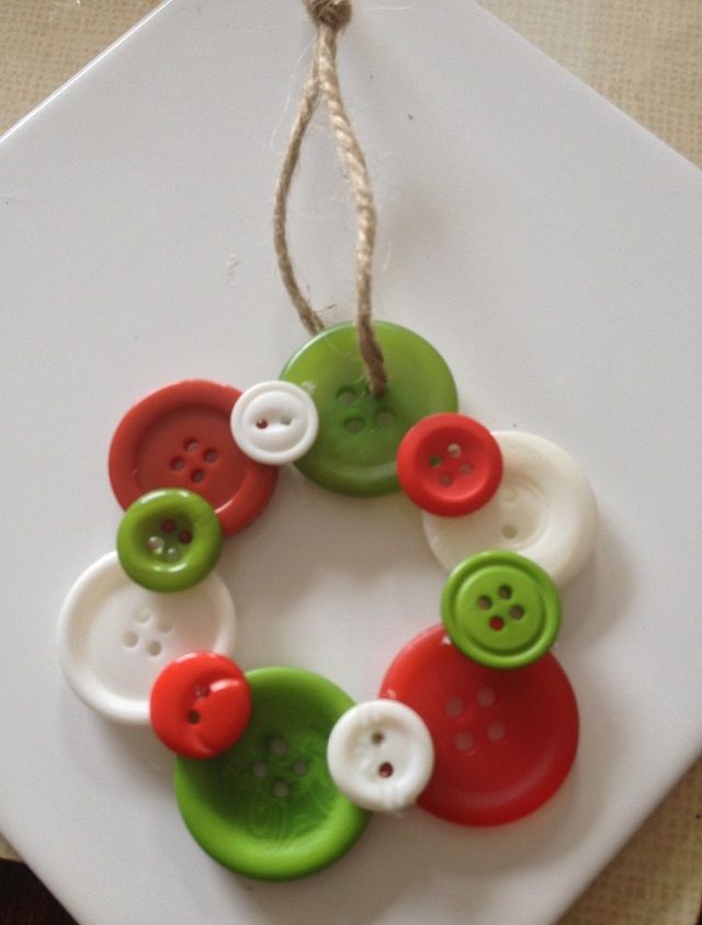 a green and red button ornament hanging from a string on a white plate