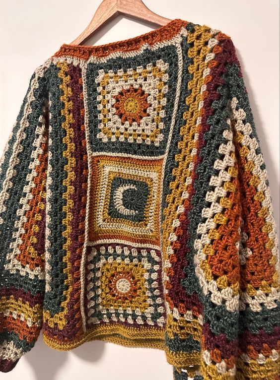 a multicolored crocheted sweater hanging on a hanger