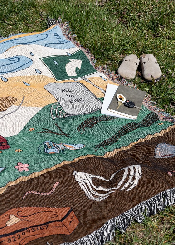 a blanket that is laying on the ground next to some rocks and a pair of shoes