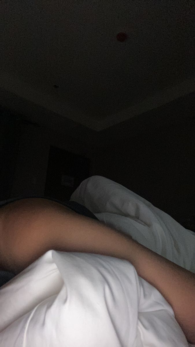 a person laying in bed with white sheets