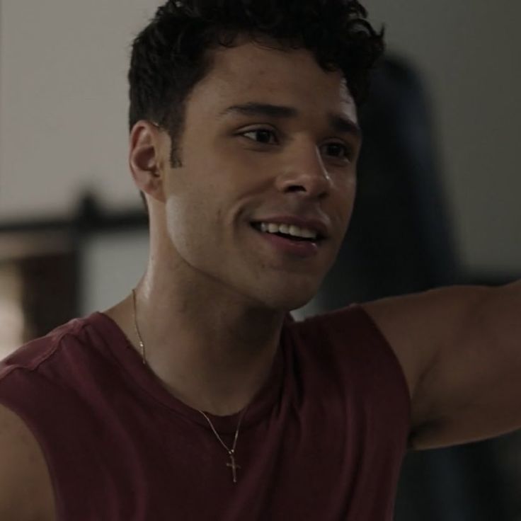 a man in a red tank top is smiling and holding his arm out to the side