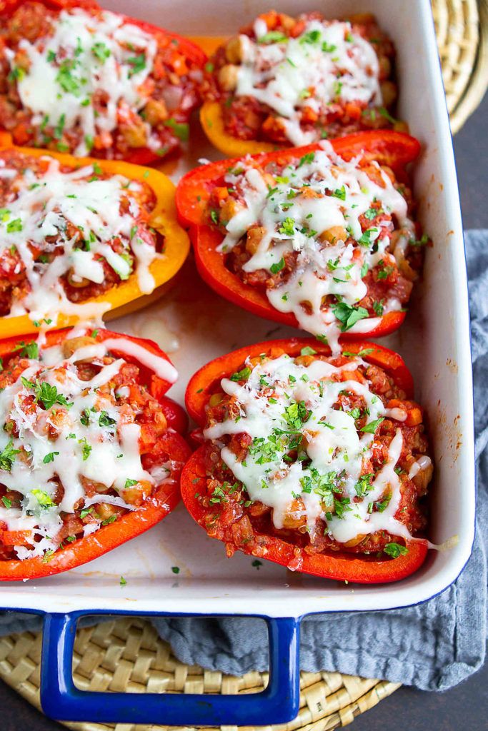 stuffed bell peppers in a casserole dish with cheese and parsley on top