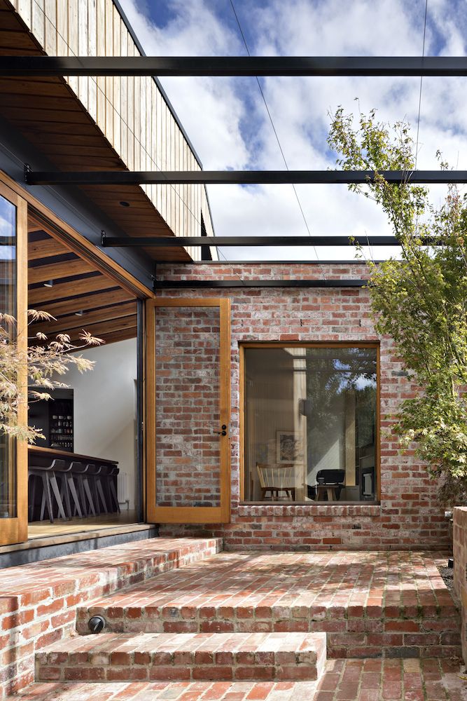 a brick patio with steps leading to the back door